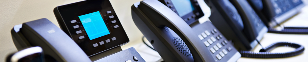 Multiple VoIP phones sitting side-by-side on a desk.