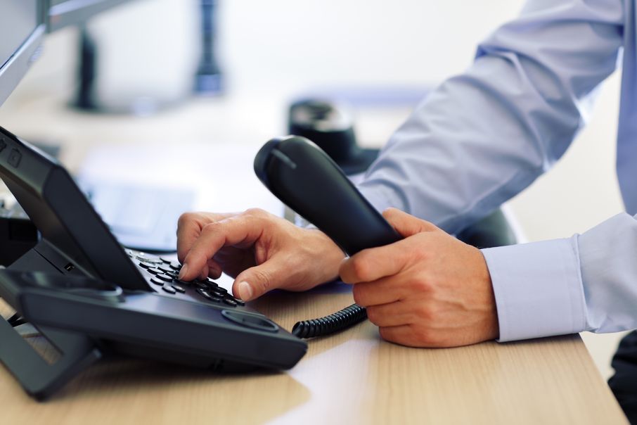 A man's hands as he dials in a number on a VoIP phone.
