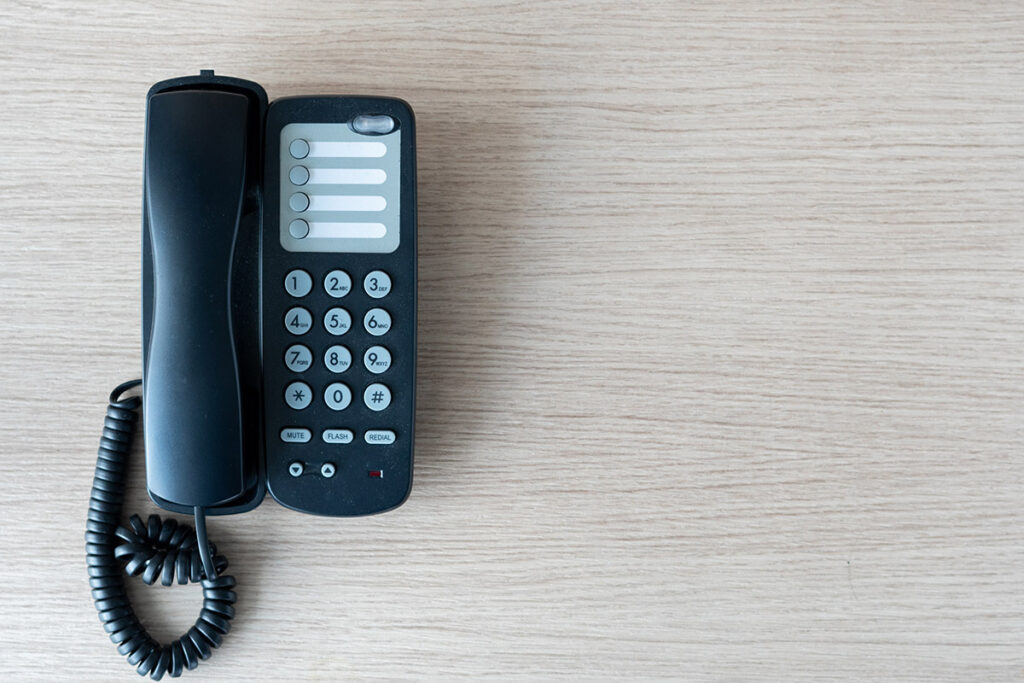 An old business phone on a wooden office desk.